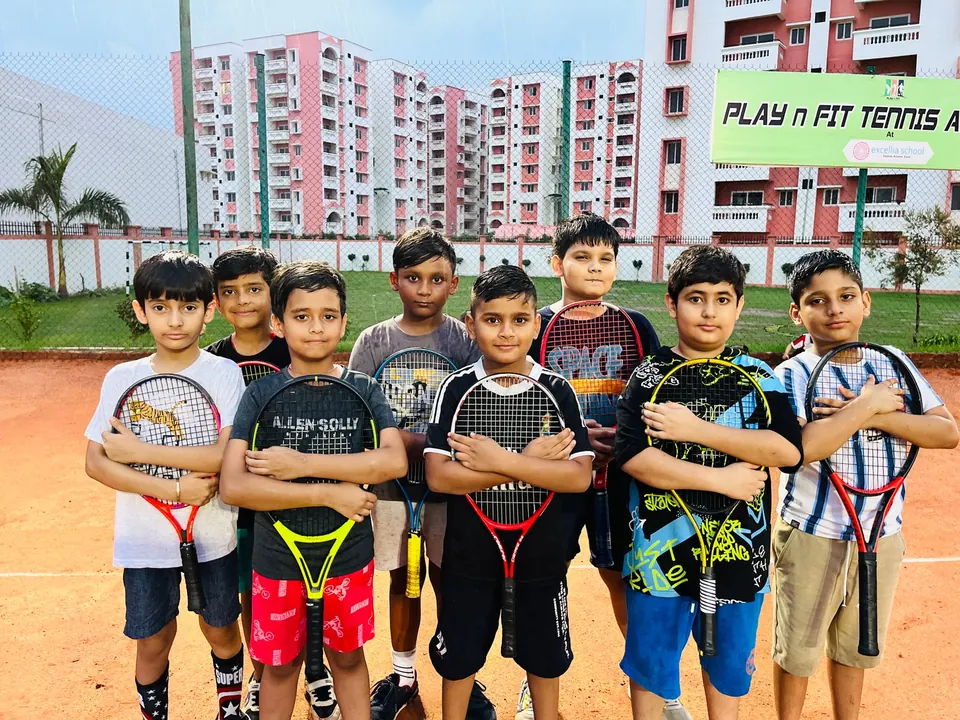 Juniors posing with racquets in front of the PLAY n FIT sign