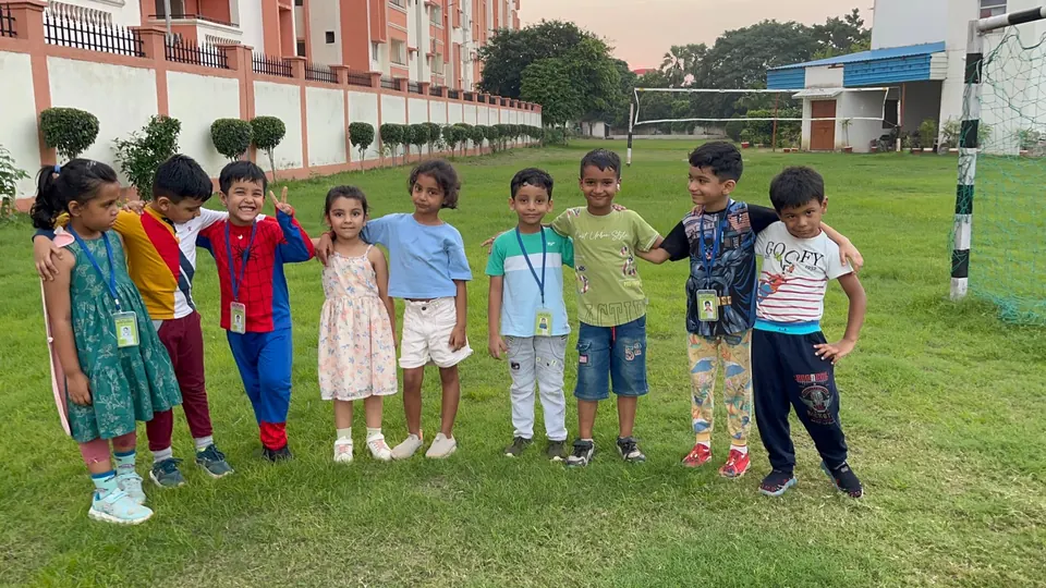 Young children lined up on the grass during a mini tennis session